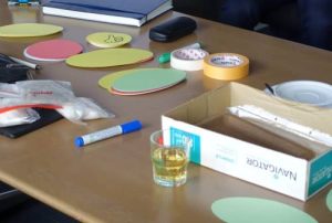 Workshoputensilien, Stifte, Zettel usw. liegen auf einem Tisch.